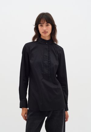 Schwarzes Langarmshirt mit einem gerafften hohen Kragen, Knopfverschluss und geradem Schnitt. Hergestellt aus glattem Stoff ohne sichtbare Muster.