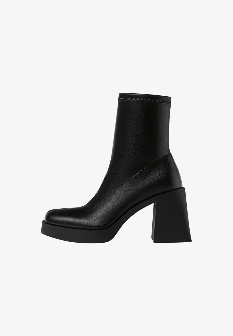 Bottine en cuir noir avec un bout carré, un talon épais en bloc et un design supérieur sans coutures.