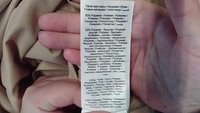 Etiqueta que muestra la composición textil: 50% poliéster y 50% poliéster reciclado. Tejido blanco con texto en múltiples idiomas e instrucciones de lavado.