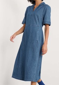 Denimmekko, jossa on kauluspääntie, lyhyet hihat ja keskipitkä helma. Valmistettu sinisestä denimistä, jossa on hienovaraista struktuuria.