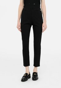 Pantaloni neri sartoriali a taglio slim, con chiusura a bottone, passanti per cintura e un sottile dettaglio logo dorato. Tessuto dalla texture liscia.