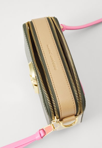 Green and beige leather crossbody bag with gold zippers, pink strap, and logo. Features a textured finish and multiple compartments.