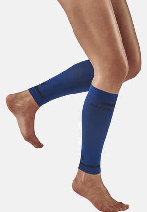Blaue komprimierende Beinschläuche mit einer gerippten Textur, die oben schwarze Akzentstreifen und ein Logodetail nahe dem Knöchel aufweisen.