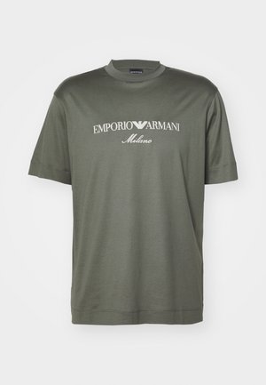 Camiseta de algodón verde oscuro con cuello redondo, con un logo blanco que dice "EMPORIO ARMANI Milano" en el pecho. Mangas cortas.