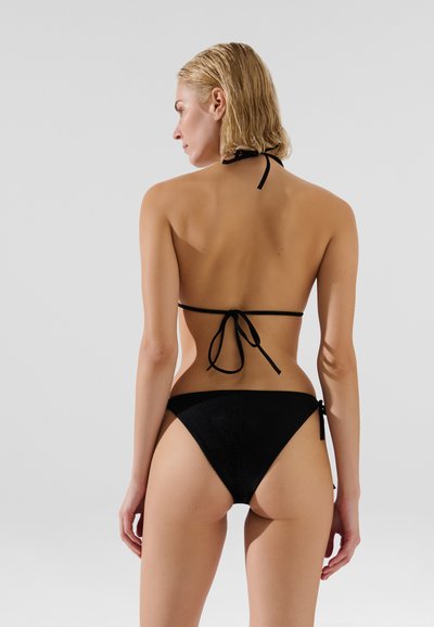 Ensemble de bikini noir comprenant un haut à nouer autour du cou, un design minimaliste et un bas taille basse avec des liens sur les côtés, fabriqué en matériau lisse et extensible.
