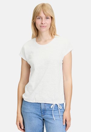 T-shirt blanc à manches courtes en tissu léger avec une texture géométrique subtile, fini par un cordon de serrage à l'ourlet.