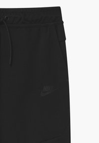 Pantaloni sportivi neri Nike con cintura regolabile, tasche frontali e un logo tonale discreto sulla gamba inferiore. Tessuto morbido al tatto.