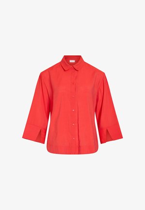 Chemise rouge à manches longues avec boutons, poignets larges fendus et col classique, présentée sur un fond blanc uni.