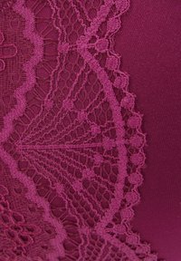 Tessuto bordeaux con dettagli in pizzo intricati, caratterizzato da un motivo floreale e bordi ondulati, che offrono un contrasto di texture.