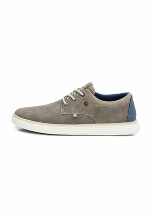 Zapatilla de lona gris con textura perforada, acentos en azul marino, cordones beige y suela de goma blanca. Presenta detalles de costura y ojales de metal.