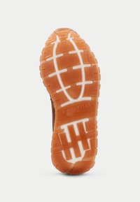 Suola di scarpa in gomma marrone con motivi di grip testurizzati. Presenta un logo prominente e elementi di trazione arancioni su uno sfondo bianco.