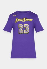 Fialové bavlněné tričko s krátkým rukávem, na přední straně s nápisem "LAKE SHOW" ve žluté barvě a číslem "23" v černé a žluté. Logo Nike na výstřihu.