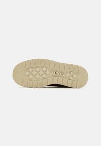 Suela de zapatilla Levi's, material de goma, color beige, patrón texturizado con diamantes elevados y surcos, logo de la marca en relieve.