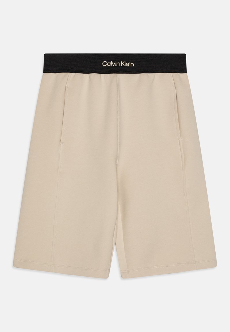 Beiga Calvin Klein-shorts med svart elastisk midjeband, med sidofickor och en mjuk, len textur. Rak skärning med rena kanter.