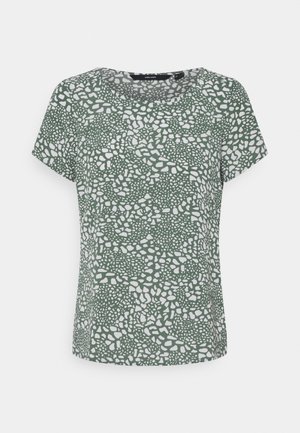 Blouse verte à manches courtes avec un motif blanc irrégulier ressemblant à des galets et un col rond, présentée sur un fond uni.