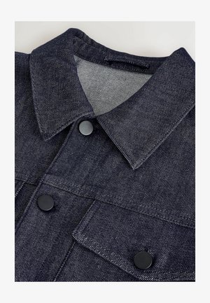 Tamsiai mėlyna džinsinė striukė su klasikiniu apykakle, dviem priekinėmis kišenėmis, juodais mygtukais ir kontrastinga vidine pamušalu su dryžuota raštą.