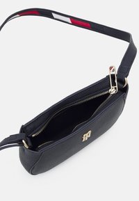 Borsa a tracolla in pelle nera con finitura strutturata, dettagli in oro, chiusura con zip e tracolla a righe contrastanti in rosso, bianco e blu.