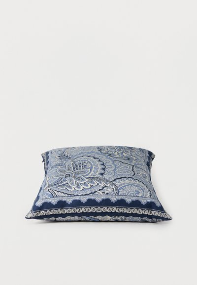 Coussin carré avec motifs floraux et cachemire bleus et blancs complexes sur un fond blanc uni.