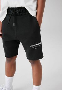 Svarta shorts i bomullsmix med elastisk midja och dragsko. Har vit logotyptext på vänster ben. Slät textur och sportig design.