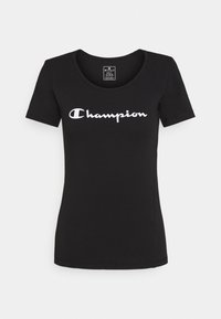 Černé tričko s krátkým rukávem vyrobené z bavlny, s bílým nápisem "Champion" v kurzívě přes hruď a kulatým výstřihem.