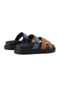 Due sandali con un design di fascette sintetiche blu e marroni, dotati di una suola in gomma nera. La suola presenta un motivo testurizzato per garantire aderenza.