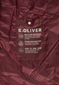 Bordeauxrode jas gemaakt van gerecycled polyester met een zakje voor het waslabel, waarop "S.OLIVER" staat, en details over de isolatie zonder ganzendaun.