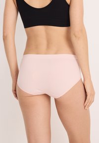 Ljust rosa kvinnors hipsterunderkläder i ett mjukt, töjbart tyg med en sömlös midja och rundade benöppningar.