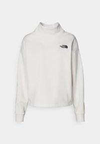 Valkoinen collegepaita, jossa on korkea kaulus ja pitkät hihat. Vasemmassa rinnassa musta logo. Pehmeästä, teksturoidusta kankaasta valmistettu.