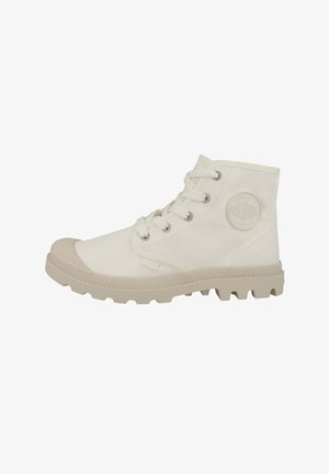 Bottines en toile blanches avec un capuchon en caoutchouc sur le bout, des lacets ronds et une semelle beige texturée. Présente un logo en relief sur le côté.