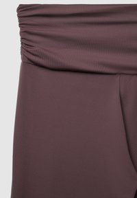 Raffiniertes, dehnbares Oberteil aus sanftem Mauve mit glatter Textur. Das Design konzentriert sich auf einen bequemen Sitz und subtile Details.