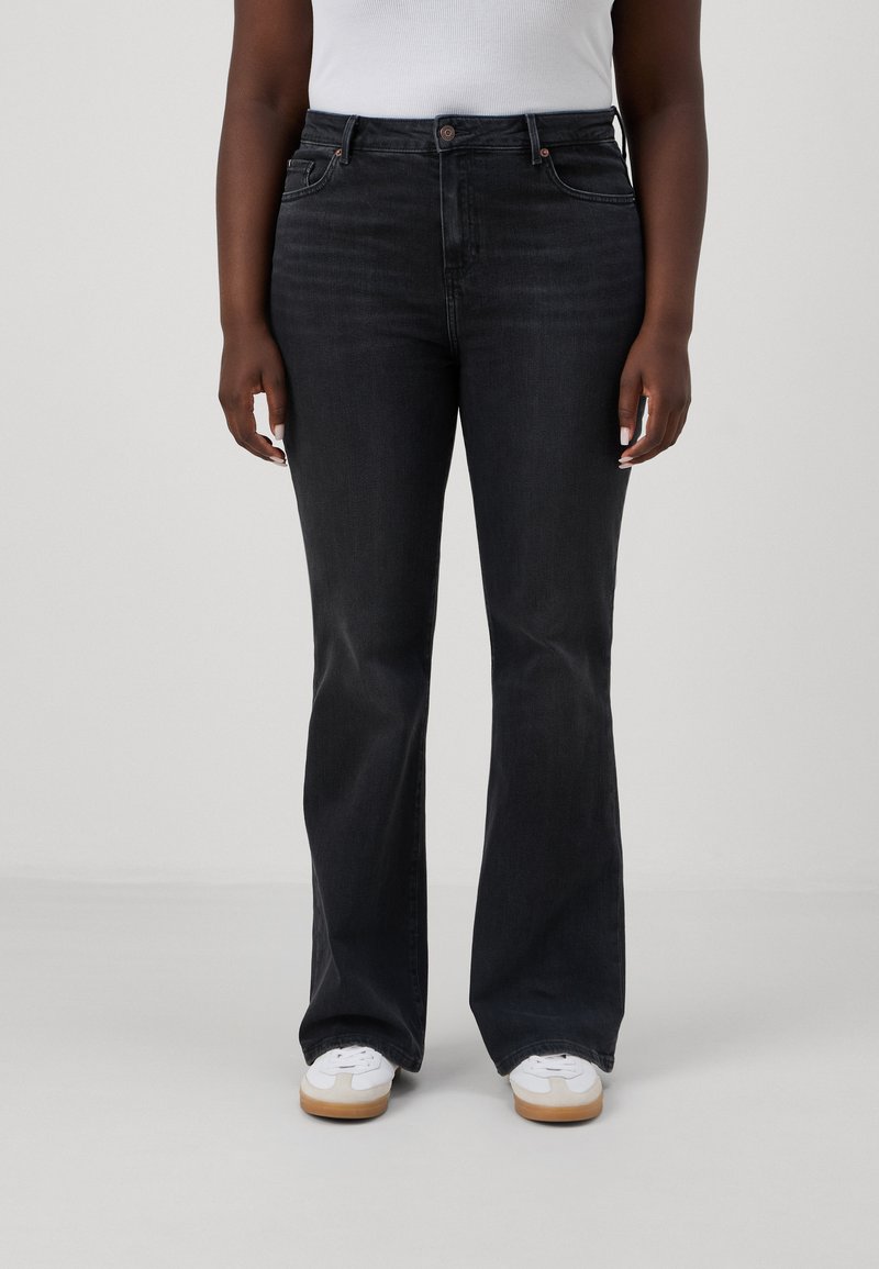 Svart flared jeans med fem lommer, knappelukking og lette falming detaljer. Bært med hvite sneakers og en enkel tank top.