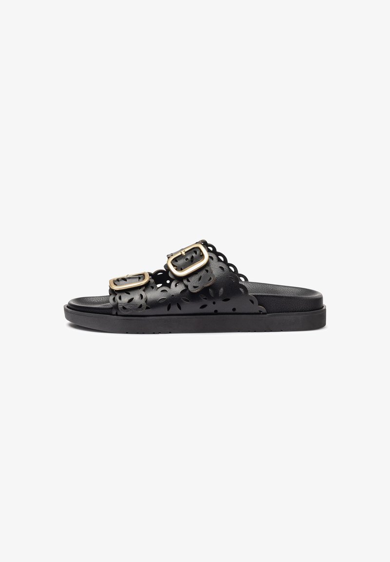 Black sandals with two adjustable buckles, floral cut-out design, flat sole, and smooth texture. Minimalist and functional aesthetic.