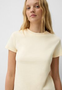 Korte mouwen, crewneck T-shirt van lichtgele katoenstof, met een aansluitend ontwerp, gladde textuur en minimalistische esthetiek.