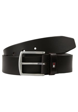 Ceinture en cuir noir avec boucle rectangulaire argentée et petit logo rectangulaire rouge, blanc et bleu sur la boucle, roulée sur fond blanc.