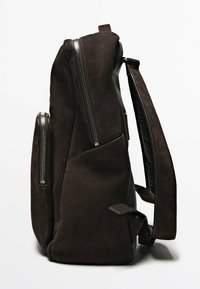Brauner Wildleder-Rucksack mit strukturiertem Oberfläche, ausgestattet mit zwei seitlichen Reißverschlusstaschen und breiten, verstellbaren Trägern für Komfort.
