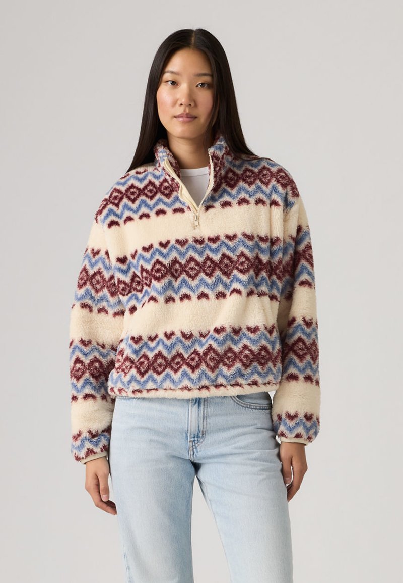 Φλις πουλόβερ με ημίκλειστο φερμουάρ, με κρεμ βάση και πολύχρωμο ζιγκ-ζαγκ μοτίβο σε μπλε και μπορντό. Μαλακό, υφασμάτινο φινίρισμα.
