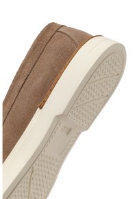 Zapato tipo mocasín de ante marrón con suela de goma blanca, mostrado de lado y por debajo, destacando el patrón texturizado de la suela.