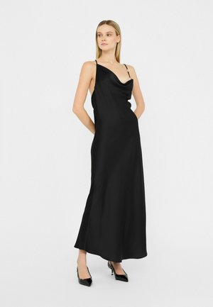 Zwarte satijnen slipdress met een couleau-halslijn, dunne schouderbandjes en een vloerlange zoom. Glad textuur, minimalistisch ontwerp, aangevuld met puntige hakken.