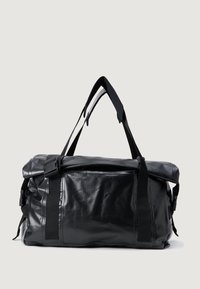 Saco duffel preto feito de material suave e durável, com uma alça ajustável, fivelas laterais e um bolso com zíper na parte superior.