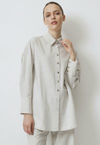 Jasnoszara, długosleeve koszula z teksturowanej tkaniny, z zapięciem na guziki z przodu, kołnierzykiem oraz dekoracyjnymi guzikami na mankietach.