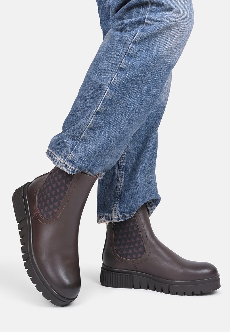 Brązowe skórzane botki za kostkę z elastycznymi panelami bocznymi w wzór trójkąta, teksturowaną gumową podeszwą i zaokrąglonym czubkiem.