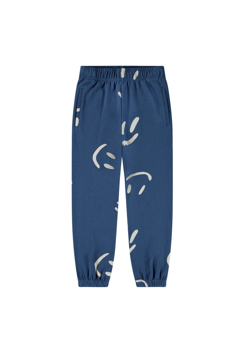 Sininen verkkarit, valmistettu puuvillasta, joissa on valkoinen abstrakti kuvio, joustava vyötärö ja joustavat hihnat nilkoissa.