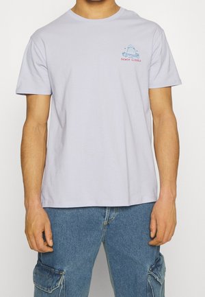 T-shirt en coton violet clair avec un col rond, des manches courtes, et un petit graphique de requin accompagné du texte "PLAGE FERMÉE" sur la poitrine gauche.