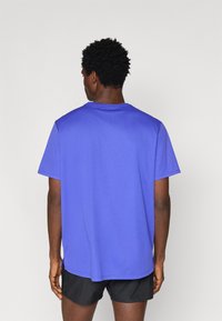 Μπλε κοντομάνικο μπλουζάκι από απαλό ύφασμα με στρογγυλή λαιμόκοψη. Η πλάτη έχει ίσια κοπή και πλαϊνές σχισμές για εύκολη κίνηση.