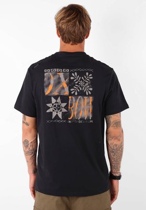 T-shirt en coton noir avec des motifs graphiques audacieux en orange et gris à l'arrière, comprenant des motifs géométriques et du texte. Manches courtes.