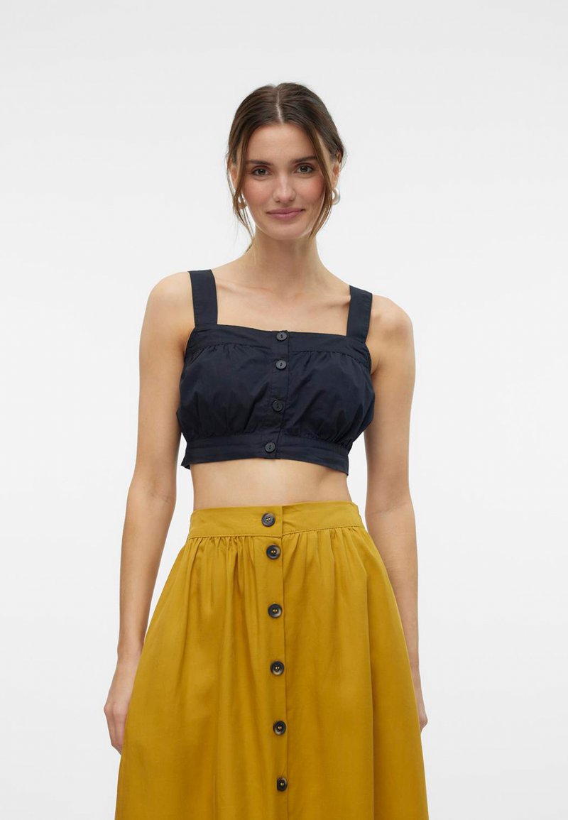 Námornícky cropped top s širokými ramienkami a detailom gombíka vpredu, v kombinácii s horčicovožltou sukňou s gombíkovým zapínaním vpredu a zberaným pásom.