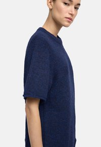 Granatowa, krótkiego rękawa, dziana bluzka o teksturowanym wykończeniu i okrągłym dekolcie, z luźnym krojem i bocznymi rozcięciami.