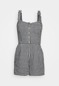 Svart och vit rutigt mönstrad jumpsuit med volangaxlar, framknäppning och sidofickor. Tätt sittande byst och lösa shorts.