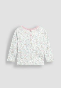 Långärmad topp i mjuk bomull med ett pastellblommönster, rundad hals och tre knappar bak, avslutad med en rosa kant.