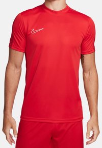 Czerwona koszulka sportowa wykonana z materiału odprowadzającego wilgoć, z krótkimi rękawami i okrągłym dekoltem, z białym logo Nike na klatce piersiowej.